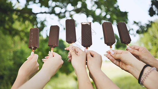朋友们把巧克力冰淇淋放在一根棍子上食物糖果女孩香草乐趣小吃女士圣代孩子沙漠图片