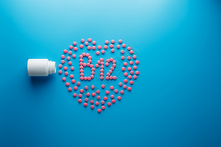 粉色平板上以B12的形式 在心脏的蓝色背景 从白色罐子里溢出字母托盘塑料地面制药愈合药物矿物营养标签图片