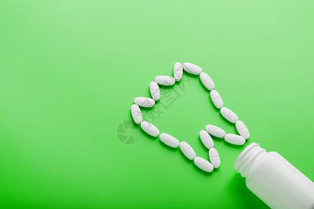 在绿色背景的白色罐子上洒出的牙齿 以维生素钙的形式呈现出来银行制药维生素丸药胶囊药品疼痛治疗矿物质药物图片