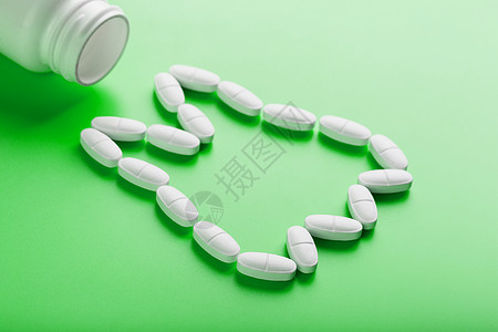 在绿色背景的白色罐子上洒出的牙齿 以维生素钙的形式呈现出来止痛药药物医生处方抗生素剂量化学品矿物质制药治疗图片