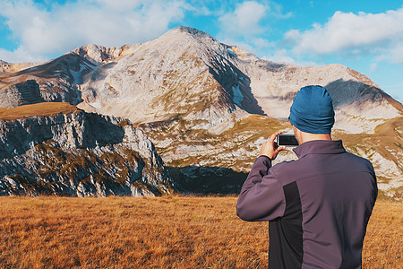 观光旅游者拍摄智能手机上云雾覆盖的山脉照片相机顶峰公园假期旅游摄影游客远足者自由国家图片