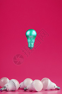 一个特殊的灯泡在粉红色背景的简单 标准的白灯泡上徘徊沉思照明技术创造力发明思考作品地球经济解决方案图片