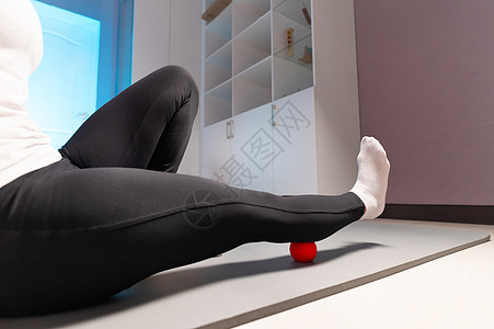 在室内使用按摩球的女运动员身上贴近自制面部 在没有按摩师的情况下进行宫间按摩 消除腿肌肉疼痛图片