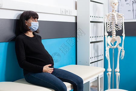孕妇在检查时戴面罩的怀孕腹部妇女;图片