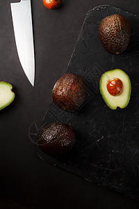黑桌上的一篮子里有开菜果和石块异国种子饮食蔬菜健康木头食物鳄梨木板美食图片