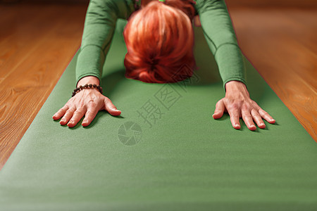 一个女人在客厅家的绿地毯上做瑜伽活动阳光孩子健康毛巾班级冥想健身房闲暇工作室图片