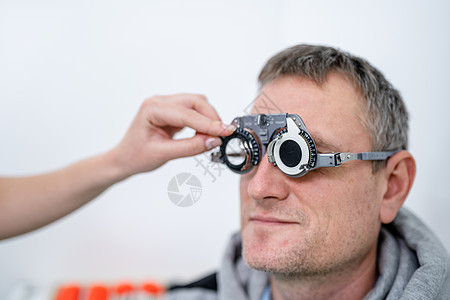 男性患者在眼科诊所接受眼科检查和眼镜处方 验光师检查患者视力和视力矫正 更换患者鼻子试镜架上的镜片成人工具验光医生办公室技术光学图片