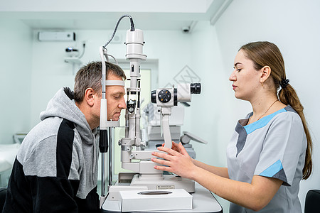 验光师在现代眼科诊所检查男性患者的眼睛 在现代诊所检查期间与男病人的眼科医生 验光概念 诊所视力检查职业近视男人考试医院医学配镜图片