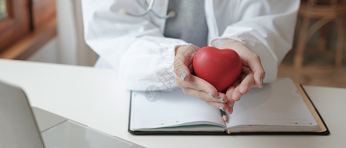 带听诊器手持心脏模型的女医生裁剪照片-心脏病专家保健概念图片
