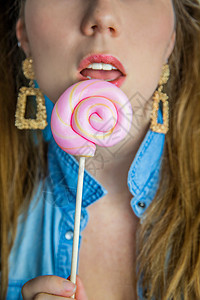 蓝色背景 糖果 糖和不健康食品概念上 一个漂亮女孩的肖像 上面有彩色粉色旋转棒棒糖硬糖食物化妆品口红指甲头发发型流行音乐美甲饮食图片