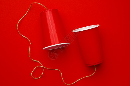 红色塑料杯 与红背景的线条连在一起细绳讲话玩具电话塑料说话绳索金属背景图片