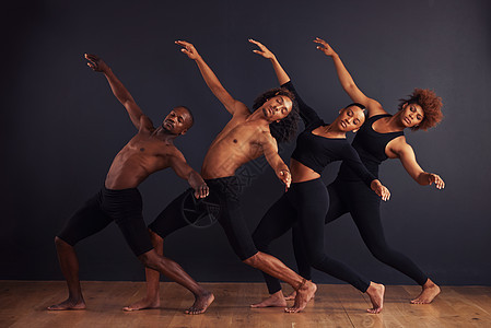 一群舞者在黑暗背景面前摆出戏剧化的姿势 他们站在黑暗背景前图片