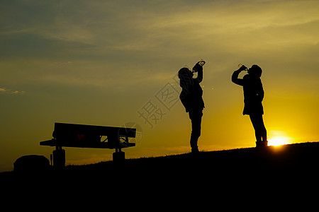 男男女女在黄昏山丘上饮水公园水分太阳供水爬坡阴影饮用水背景男人三鹰图片