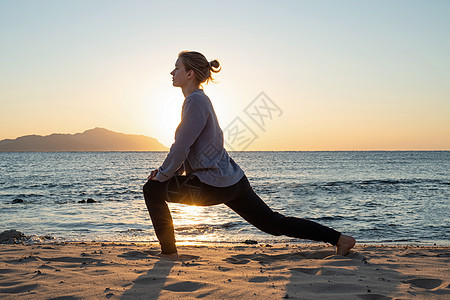 年轻健康的女人 在日出时在海滩上做瑜伽海洋太阳训练成人姿势天空活力女孩生活身体图片