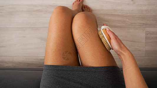 妇女握着木笔刷子 腿上做干按摩自我照顾概念消脂奶油女性卫生浴室配饰剥皮皮肤护理组织图片