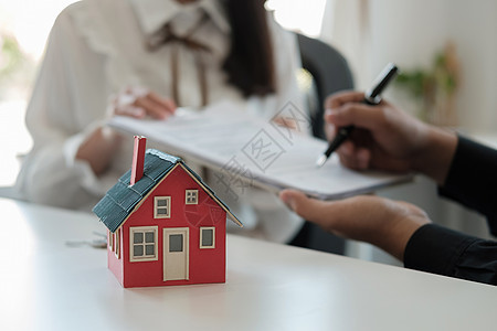 房地产经纪人指着一份合同文件 建议客户签上自己的名字 客户签署购买或出售房屋的协议合同签名 选择性的焦点图片