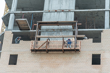 俄罗斯莫斯科 05 10 2021 建筑物的修复 重建和维修 建筑工人站在升降平台上铺砖 房屋修复施工现场图片