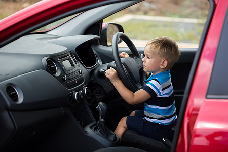 可爱的小男孩驾驶他父亲的车旅行汽车活动快乐婴儿男人腰带喜悦危险司机图片