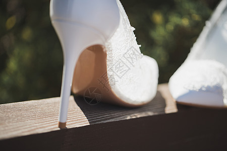在泳池背景的木梁上 穿着优美白色婚礼鞋图片