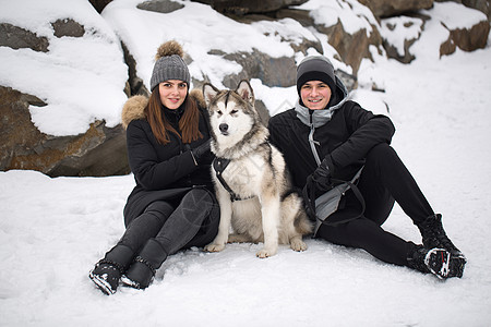 美丽的家庭 一个男人和一个女孩与狗一起在冬季森林玩狗西伯利亚哈斯基公园乐趣石头喜悦夫妻幸福男人帽子松树动物图片
