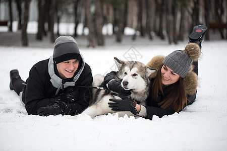 美丽的家庭 一个男人和一个女孩与狗一起在冬季森林玩狗西伯利亚哈斯基公园松树笑声动物夫妻乐趣假期幸福夹克女孩图片