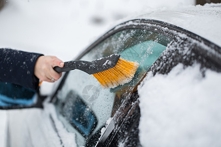 女人在冬天从车里擦雪玻璃天气安全驾驶女性雪堆成人刮刀扫帚蓝色图片