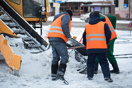 拖拉机从雪中清理道路 挖掘机清理城市中大量积雪的街道 工人在冬天从道路上扫雪 从暴风雪中清洁道路风暴雪堆雪机机器降雪路人路面卡车背景图片