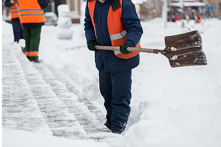 市政部门特殊形式的雇员正在用铲子清除人行道上的雪雪 以特别形式提供市政服务街道男性投掷者工人雪堆橙子降雪职业风暴院子图片