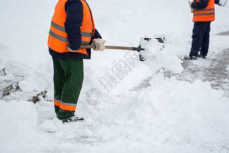 市政部门特殊形式的雇员正在用铲子清除人行道上的雪雪 以特别形式提供市政服务暴风雪降雪城市街道天气季节工作行动车道职业图片