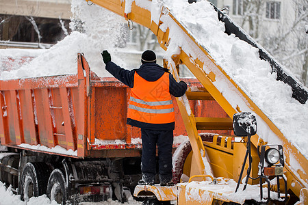 爪式装载机车辆清除道路上的积雪 穿制服的社区服务人员帮助将雪装进卡车图片