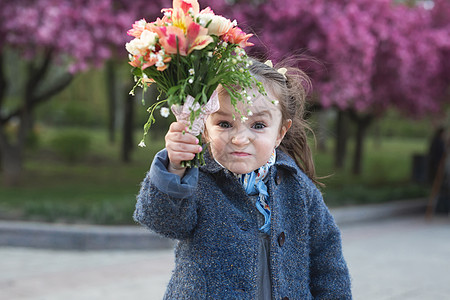 春泉公园的小女孩正在威胁摄影机 挥舞一束花束 挥舞着一束鲜花图片