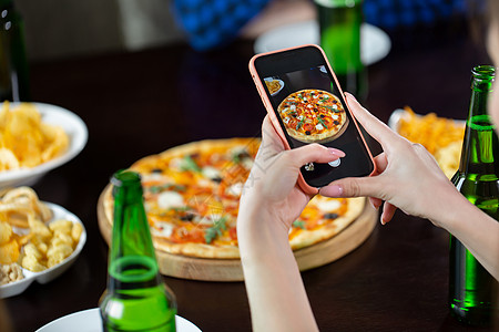 女人用智能手机拍比萨饼图片