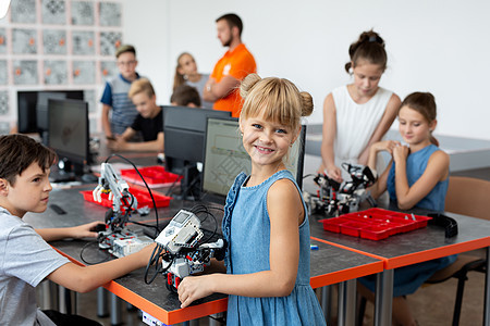 一个快乐的女学生在机器人课上的肖像 她拿着一个机器人 它是由在计算机上编程的塑料部件组装而成的笔记本女孩工程孩子技术学校学习活动图片