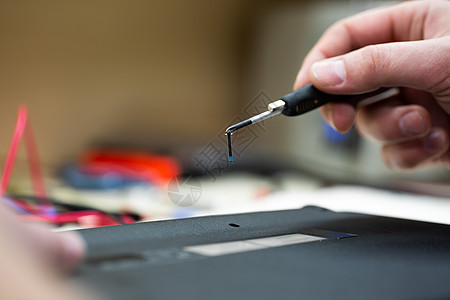 一名男工程师在车间修理一台膝上型电脑 用螺丝起子拆卸笔记本电脑的封面维修木板处理器内存技术男人硬件技术员电缆螺丝刀图片