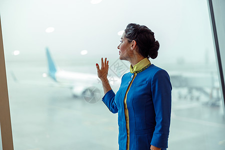 女空姐在机场候机楼的窗口上举手运输工人飞机场航程航空公司空气航空服务员工作玻璃背景图片