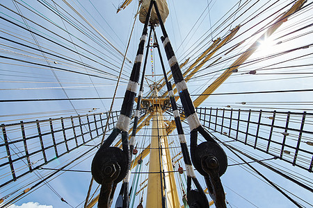 从下面看一艘旧帆船的巨大桅杆 许多绳索从上面垂下来 在阳光明媚的日子里背景是蓝天甲板码头港口血管运动员旗帜游艇巡航运输赛艇图片