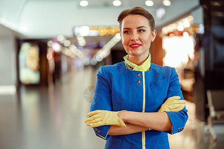 在机场候机站站着的愉快的女空勤人员航班航空公司飞机工人腰部女性旅行航空服务员航程背景图片