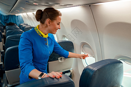 微笑的女性空姐在飞机上特写窗口旅游服务员职业空气运输航程喷射窗户成人沙龙图片
