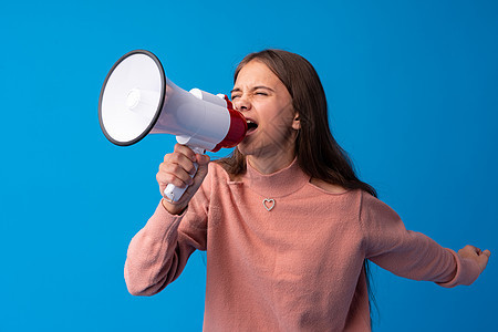 女孩在蓝色工作室用扩音器做广告青少年喇叭公告扬声器女士注意力说话青年演讲嗓音图片