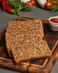 黑棕色背景的木板上的烤黑麦谷物面包 烧焦了乡村美食饮食木头脆皮烹饪种子厨房营养早餐图片