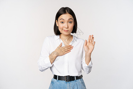 可爱的年轻女办公室职员的形象 亚洲女学生举起手 手掌放在胸前 给自己起名字 介绍 做出承诺 站在白色背景上企业家女孩工作室广告女图片