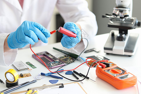 一个身穿制服 手拿着电压计和红色电池的男子图片