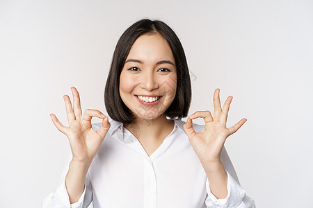 特写亚洲女孩的头像 表现出好的 好的手势和满意的微笑 推荐 高兴 赞美和恭维 白色背景广告企业家手臂女士女性人士公司售货员员工标图片
