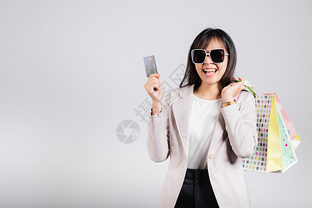 持有在线购物袋和信用卡以支付手头付款的有戴眼镜自信沙巴笑脸的妇女购物狂享受零售女孩销售奢华顾客工作室店铺购物中心图片