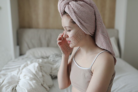 头部有毛巾的年轻女子在脸皮上涂奶油健康浴室女性皮肤科身体温泉面具口罩女孩化妆品图片