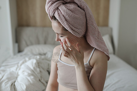 头部有毛巾的年轻女子在脸皮上涂奶油美容水分浴室口罩皮肤黑发擦洗温泉福利化妆品图片