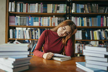 一个拿着书架的女孩 图书馆里的一个学生同学阅读学习女性女士青少年书柜学校文学知识图片