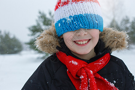 穿着明亮冬衣和红围巾的快乐男孩松树季节降雪衣服夹克喜悦闲暇行动童年雪花图片