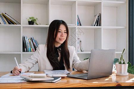 亚洲商务女性在办公室使用笔记本电脑处理财务文件 做会计和计算的女会计师 簿记员进行计算 储蓄 金融图片