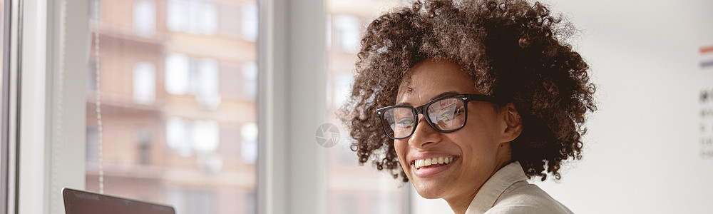 女证件照快乐的年轻女子在靠近窗口工作时持有证件桌子雇主女性商务微笑记事本职业管理人员就业眼镜背景